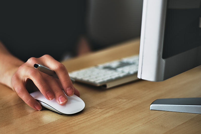 Person sitting at desk, using computer for therapy website design